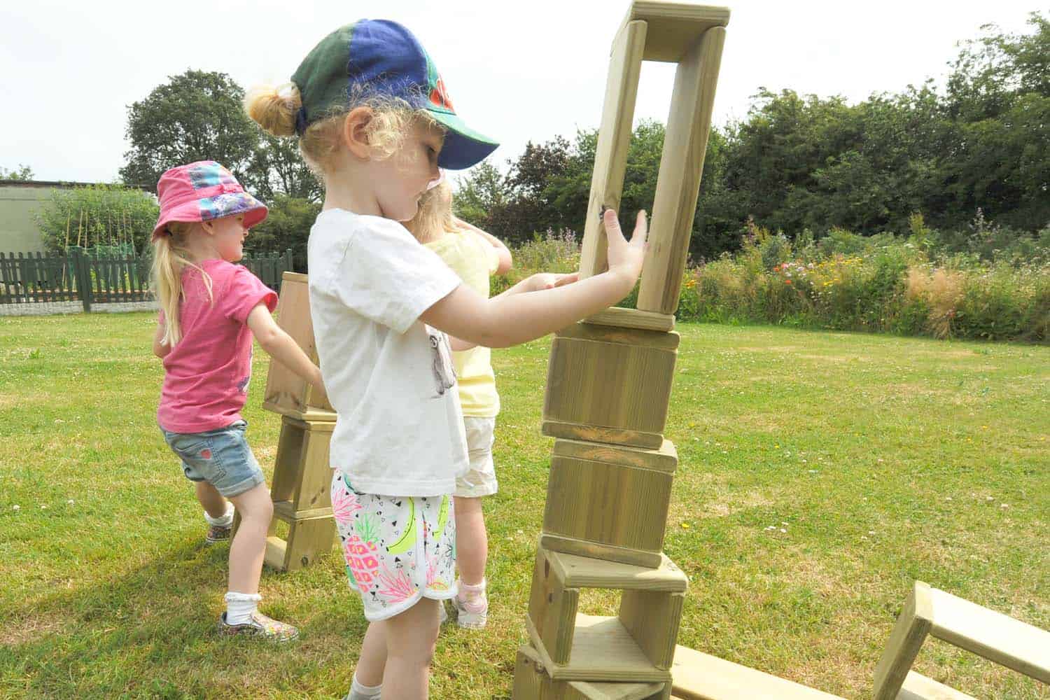 three children creating towers from wooden building blocks