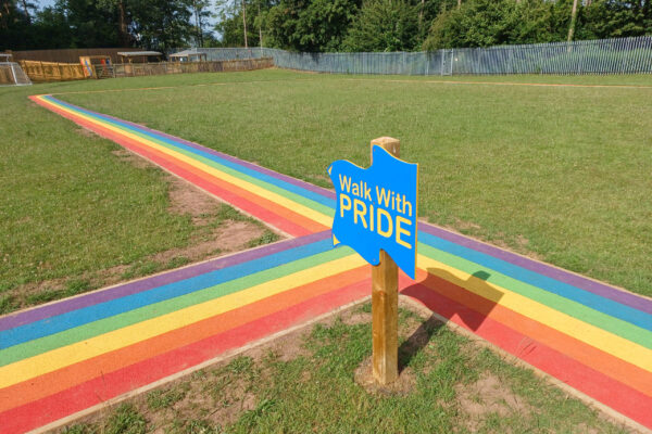 Rainbow running track with a 'walk with pride' sign.