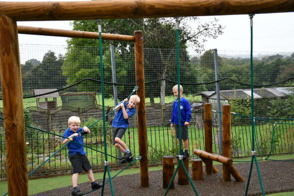 Three children playing on rope trail outdoors